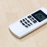 Air condition remote on the wooden table in the meeting room and setting temperature at 25 degree celcius.