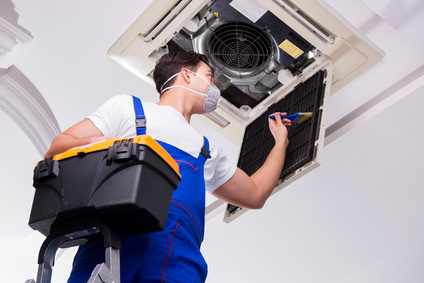 Worker repairing ceiling air conditioning unit